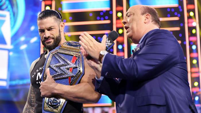 Paul Heyman on the microphone beside Roman Reigns on SmackDown